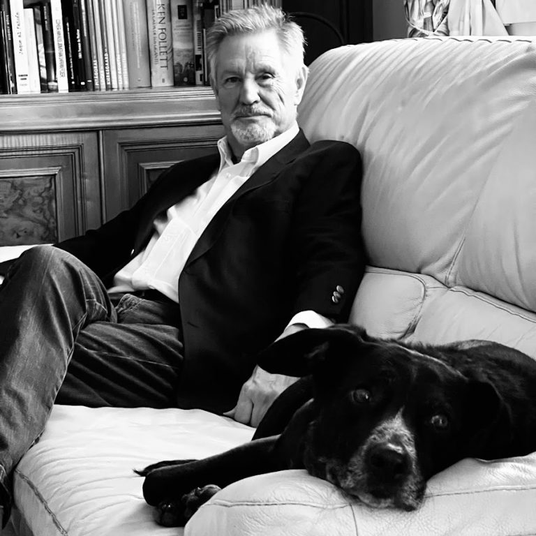 Fotografía de contraportada del escritor Jaime Tino Pouso, sentado en un sofá junto a un perro.