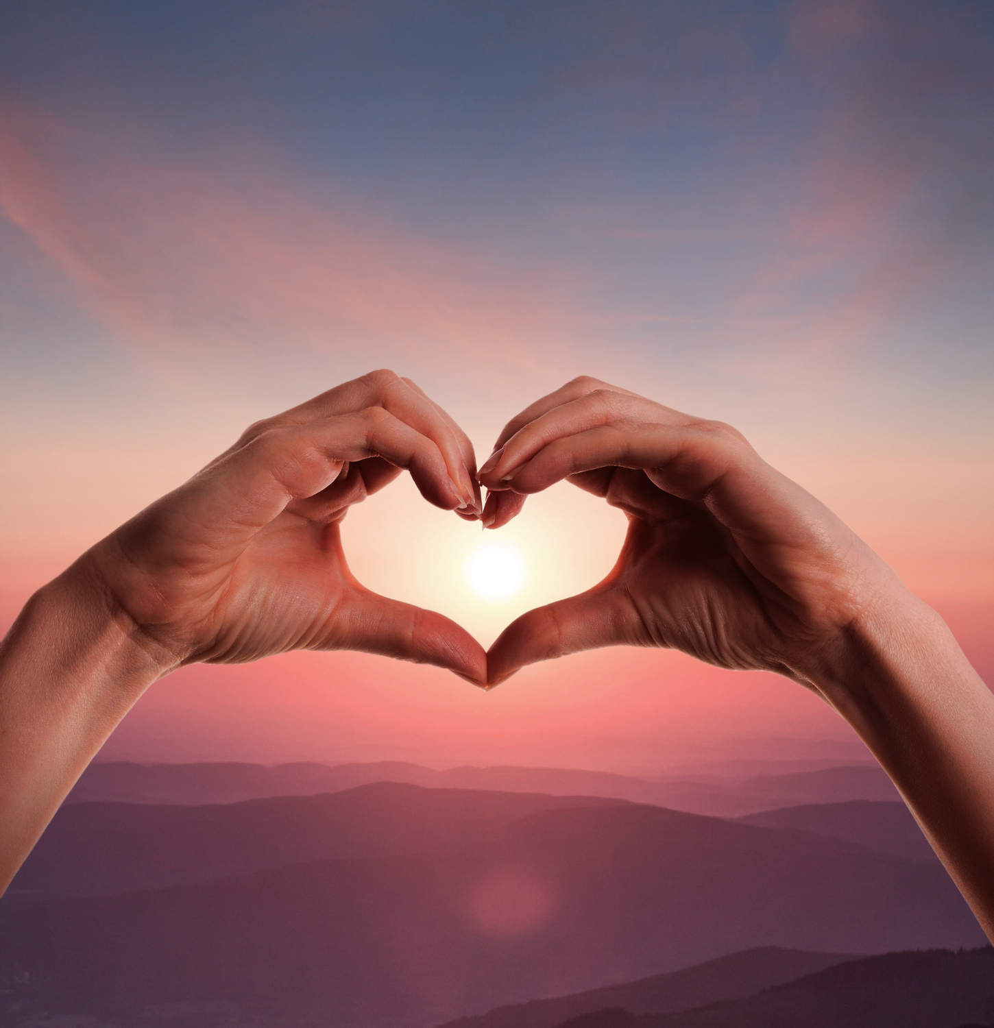 dos manos formando un corazón al atardecer